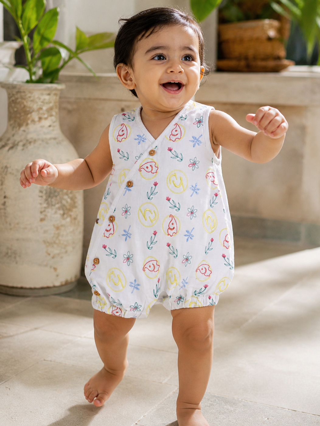 Baby wearing Hopebow ivory printed romper with bib detail