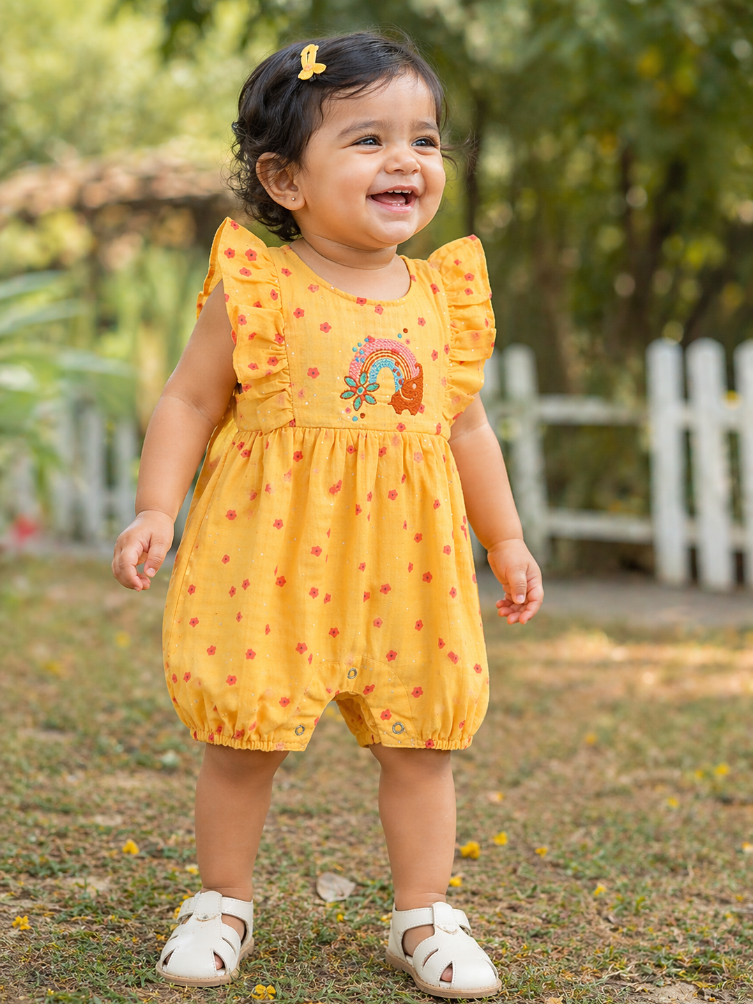 Baby girl wearing Hopebow yellow embroidered rainbow romper