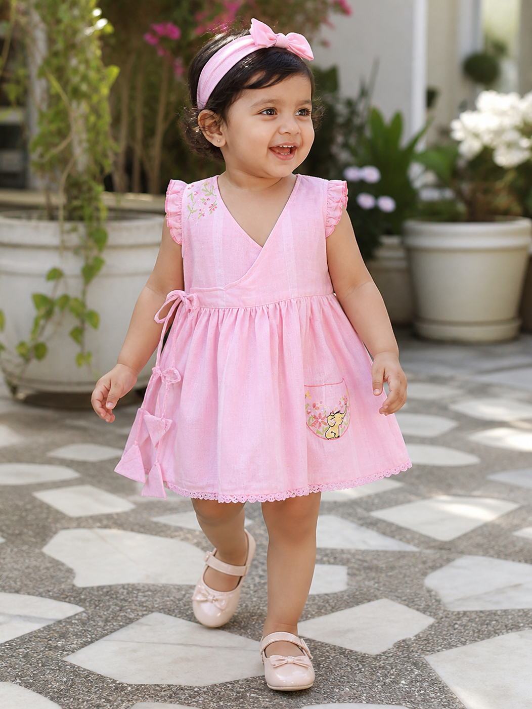 Baby girl wearing Hopebow rosewater pink dress and bow headband