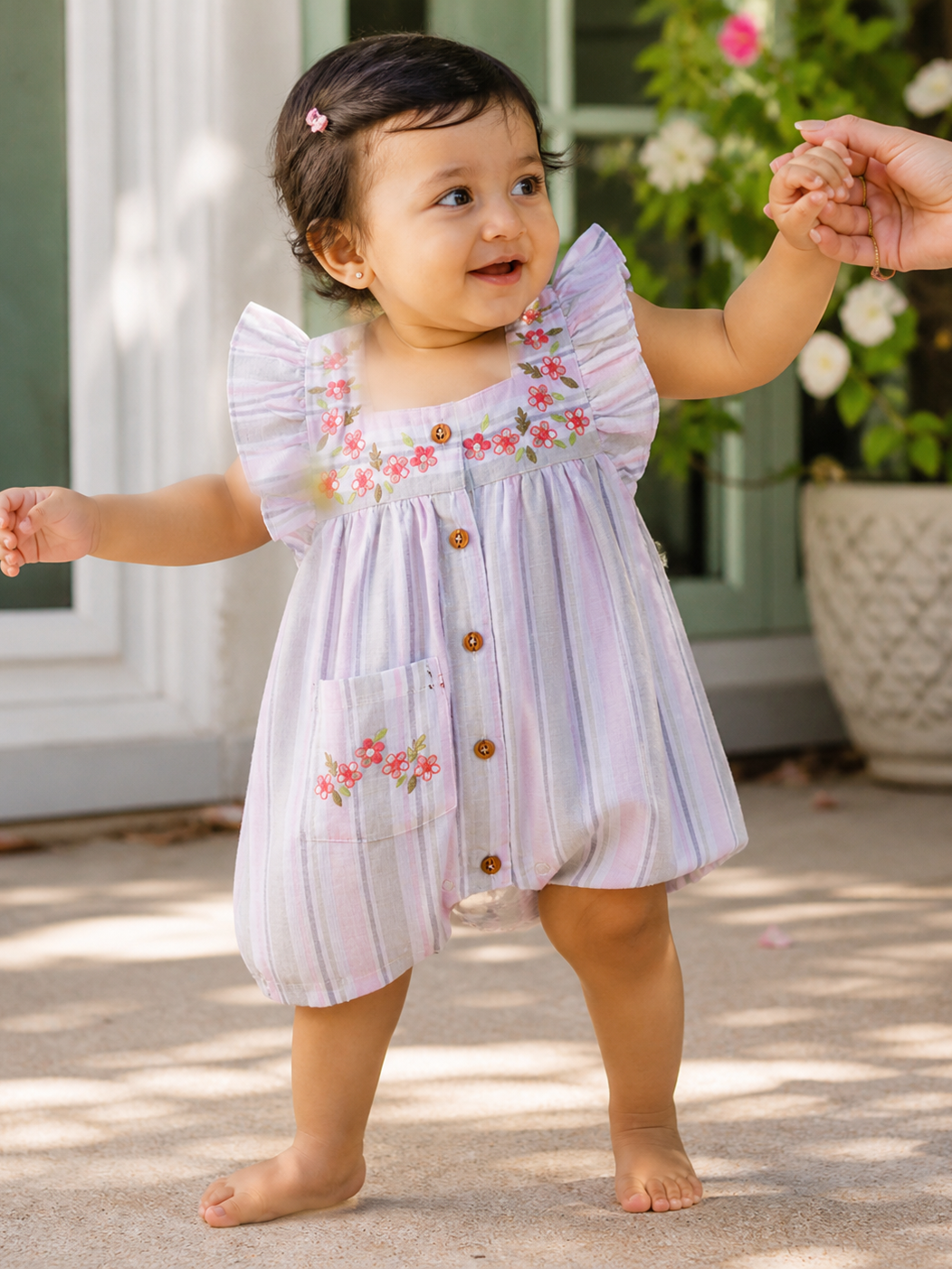 Baby girl wearing Hopebow pastel striped romper with floral yoke