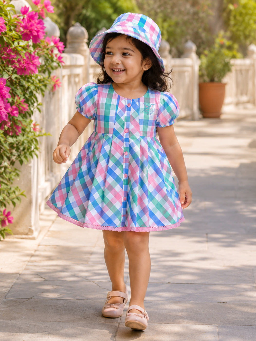 Baby girl wearing Hopebow pastel check smocked frock and hat