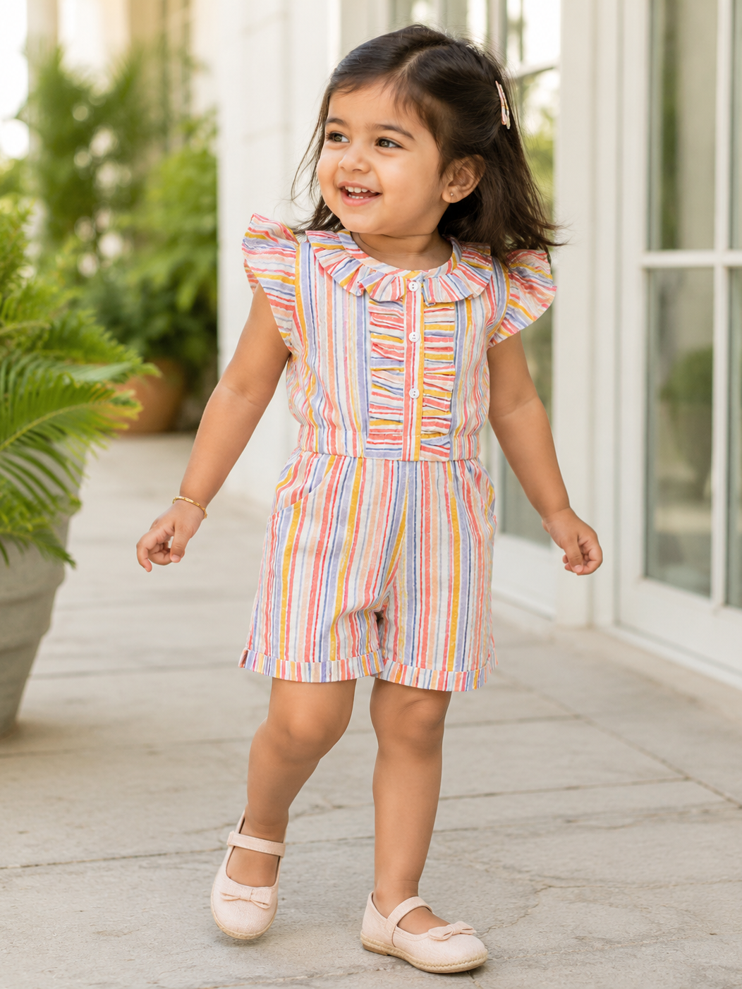 Girl wearing Hopebow pastel stripe ruffle romper